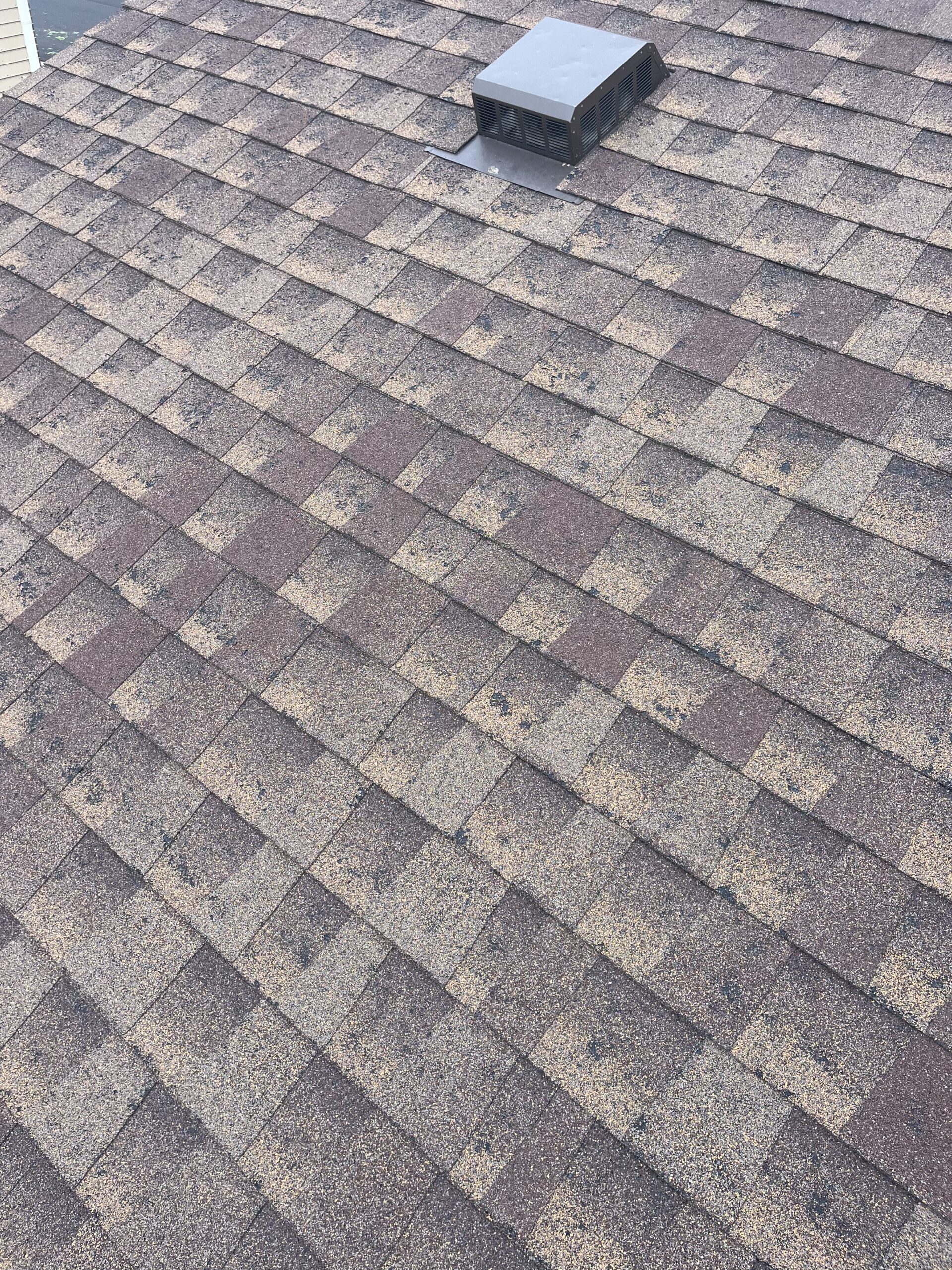 Close-up of asphalt shingles damaged by hail on a residential roof in Aurora, Colorado